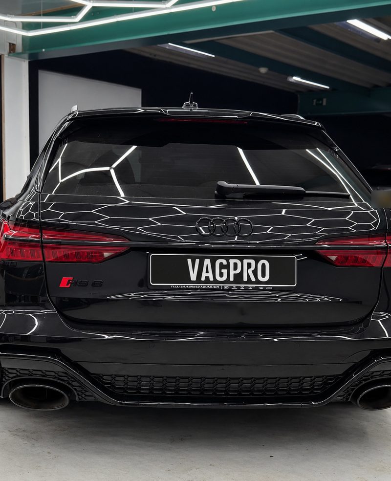 Achterkant van een zwarte Audi RS6 Avant met VAGPRO-kentekenplaat in de werkplaats