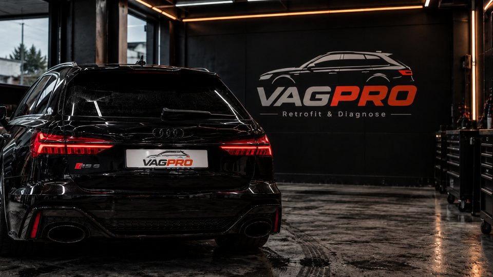Zwarte Audi RS6 Avant met VAGPRO-kentekenplaat in een donkere werkplaats, voor een muur met het VAGPRO-logo en de tekst Retrofit & Diagnose