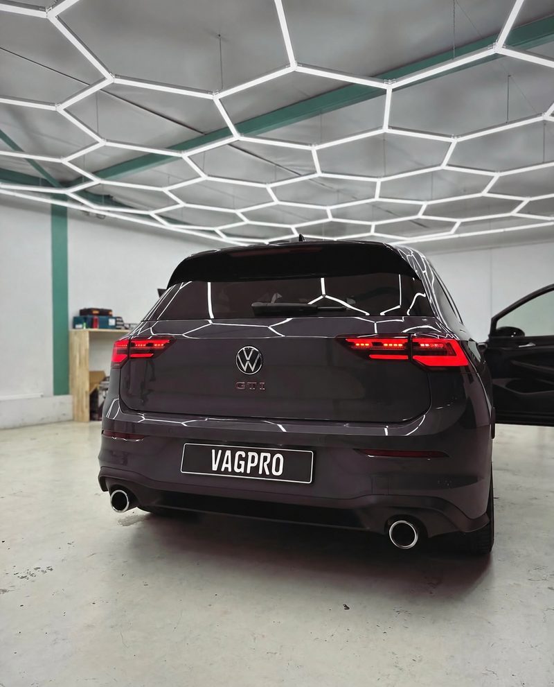 Achterkant van een grijze Volkswagen Golf GTI met VAGPRO-kentekenplaat in de werkplaats