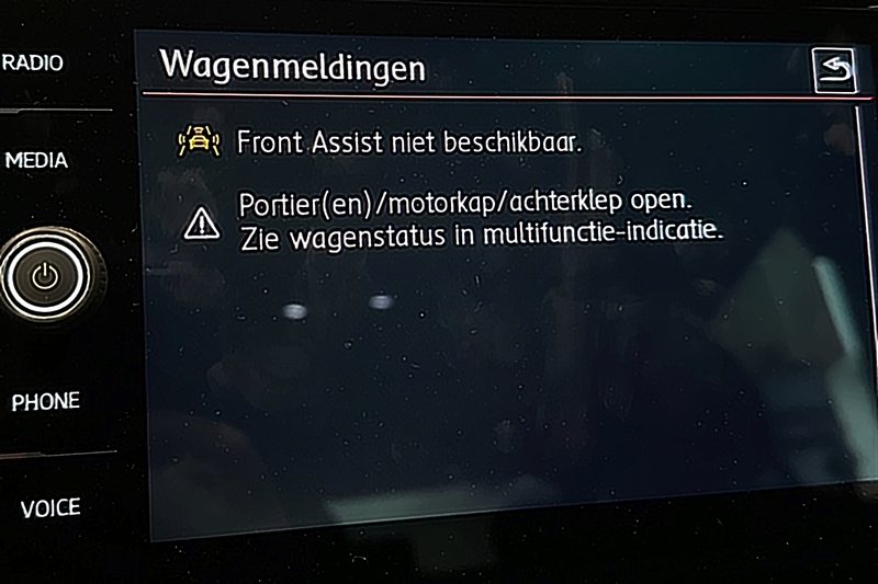 Infotainmentscherm van een Volkswagen met wagenmeldingen: Front Assist niet beschikbaar, en een portier, motorkap of achterklep open